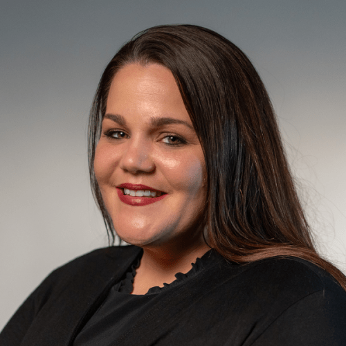 Photo headshot of Alexandrea Adkins in a black top against a gray background.